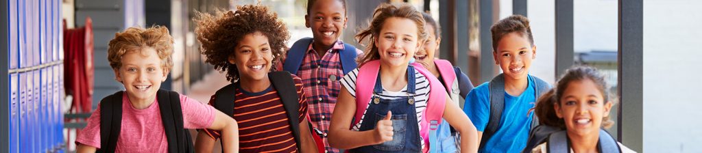 Group of smiling students running down a school hallway