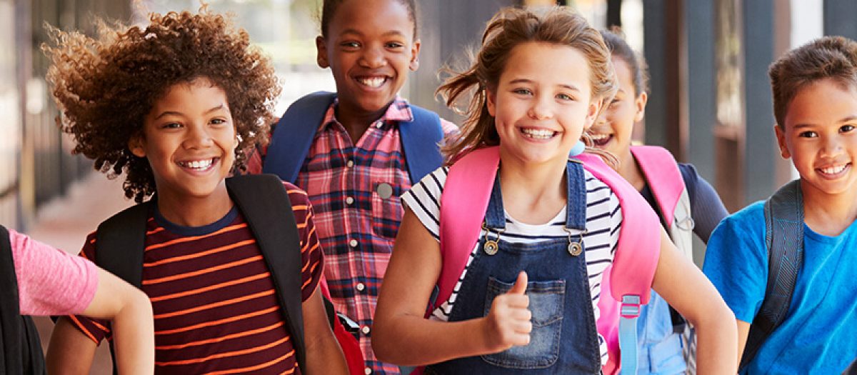 Group of smiling students running down a school hallway